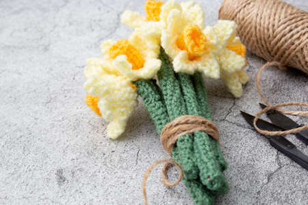 Knitted wool daffodil flowers with garden cutters and string.  On a concrete backgroundの写真素材