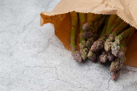 Asparagus in a brown paper bag on a concrete background. Environmentally friendly recycle packaging concept.の写真素材