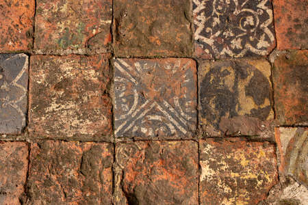 Medieval clay floor tiles with hand painted patterns.  Old floor tiles distressed and vweathered from exposure to the elementsの写真素材