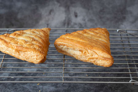 Apple turnover, freshly cooked, cooling down on a metal cooling rack. On a dark stone backgroundの写真素材