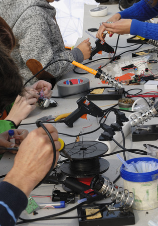 Children using glue guns are making different electronic thingsの写真素材