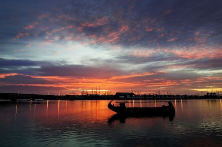 a sunrise cloudy sky on the river and a single boatの写真素材