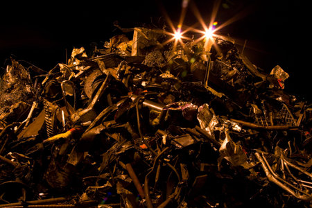 heap of rusty metal scrap and lights at nightの写真素材