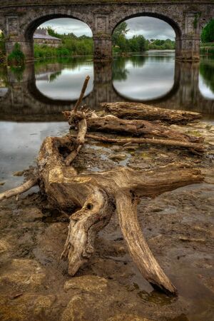 old wooden snag and stone bridge detail on Nore river in Kilkenny, HDR imageの写真素材