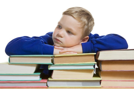 young boy sitting at the desk with hands on top of  books