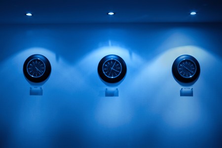 row of clock on the wall illuminated by lampsの写真素材