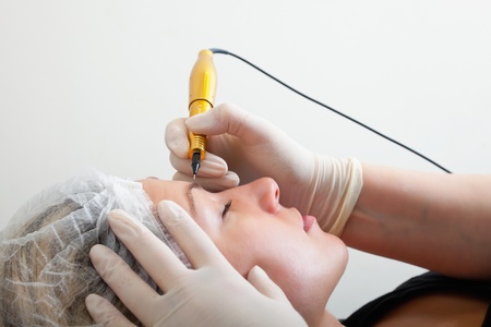 Cosmetologist making permanent makeup on woman's faceの写真素材