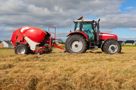 huge tractor collecting haystack in the field at nice blue sunny day
