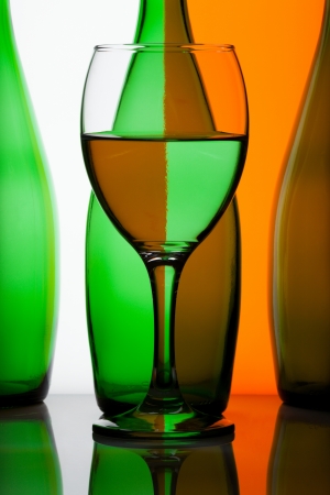 Green bottles with glass of water on grey and orange backgroundの写真素材