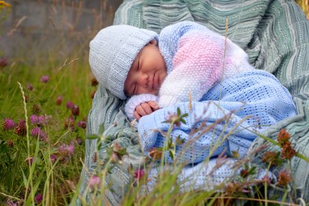 newborn baby boy in knitted jacket asleep at the gardenの写真素材