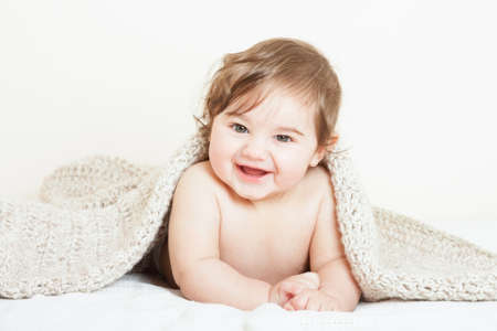 Smiling baby boy covered with knitted blanketの写真素材