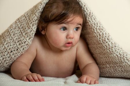 Cute baby boy covered with knitted blanketの写真素材