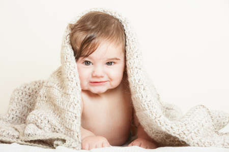 Smiling baby boy covered with knitted blanketの写真素材