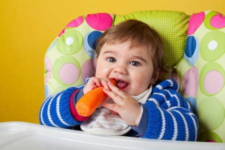 Cute baby eating organic carrot, close-upの写真素材