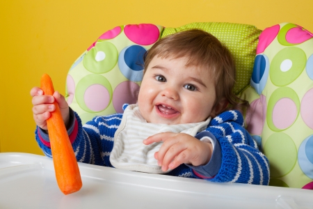 Cute baby with organic carrot, close-upの写真素材