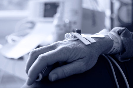 Close up of a patient hand with needle for intravenous dropper in hospital, monochromatic