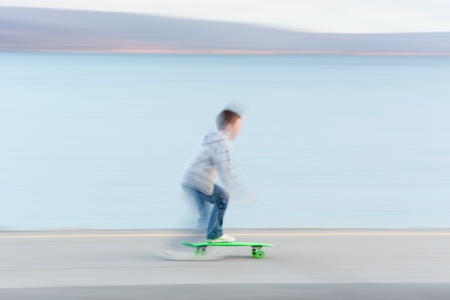 Boy riding skateboard at the bank of the ocean  Blurred motion, person is not recognizableの写真素材