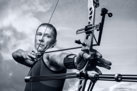 Tough man with bow and arrows, close up with cloudy sky at background. Monochromaticの写真素材