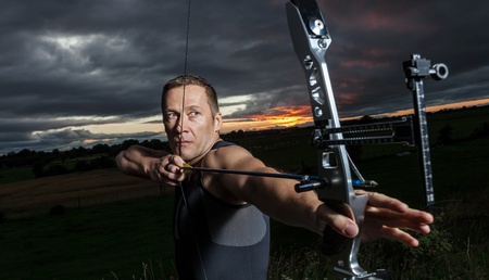 Cose up of Tough man with bow and arrows during dramatic cloudy sunset.の写真素材