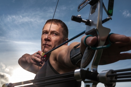 Tough man with bow and arrows, close up with cloudy sky at backgroundの写真素材
