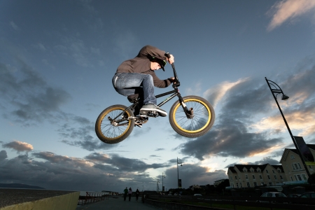 Young man performs BMX stunts during sunset at the street の写真素材