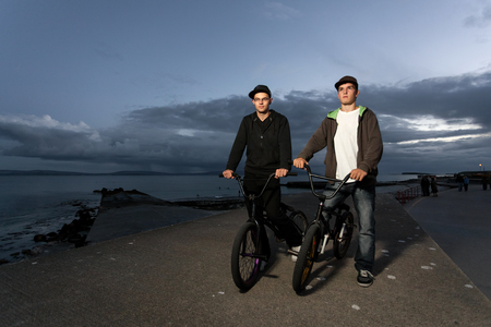 Two Young men with bicycles prepare to BMX stunts at the streetの写真素材