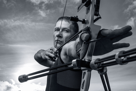 Tough man with bow and arrows, close up with cloudy sky at background. Monochromaticの写真素材