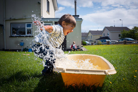 Young boy playing with water in the back gardenの写真素材