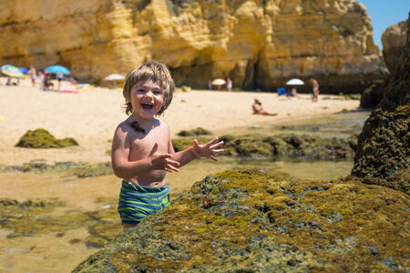 Young Boy having fun on the beach at sunny hot day.の写真素材