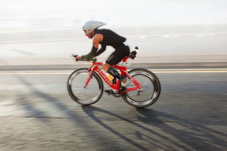 Athlete riding bicycle at sunny day on coastal road, blurred motionの写真素材