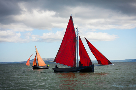 Traditional wooden boats Galway Hooker, with red sail, compete in regatta. Ireland.の写真素材