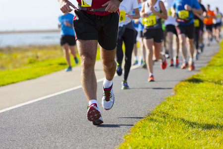 Group of runners compete in the race on coastal roadの写真素材