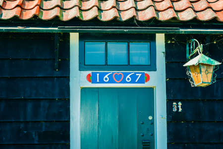 doors of house painted with a year of construction and lantern, with red roofの写真素材