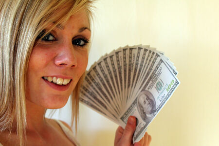 young woman holding alot of one hundred dollar bills in her handの写真素材