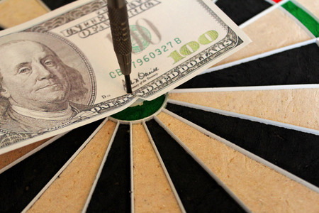 hundred dollar bill in the bulleyes of a dart boardの写真素材