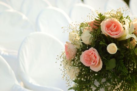 Empty white covered chairs and a bouquet of flowersの写真素材