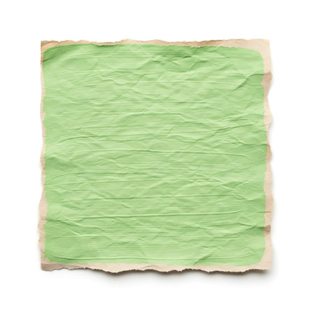 A close-up, top-down view of a crumpled piece of green paper with torn, rough edges, isolated on a clean white background. The paper shows texture and crease marks.の素材