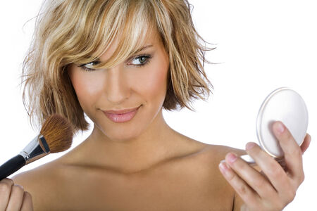 Gorgeous woman applying blush and holding a pocket mirror isolated on whiteの写真素材