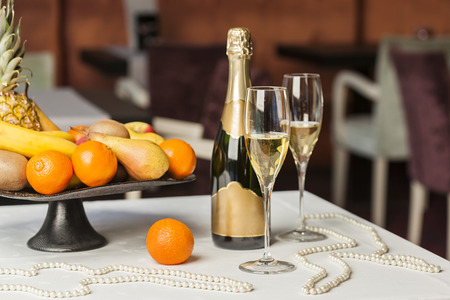 Champagne, fruit and pearls on tableの写真素材