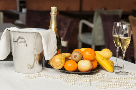 Champagne, fruit and bead necklace on tableの写真素材