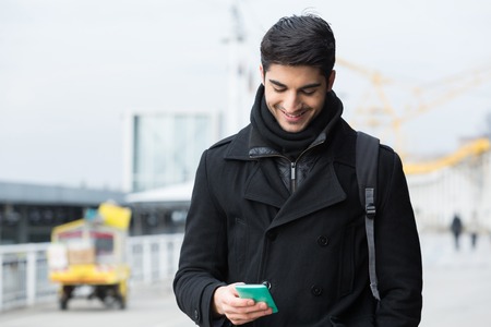 Young man with smart phone on city street in winterの写真素材