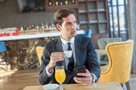 Handsome young businessman using his cell phone in hotel cafeの写真素材