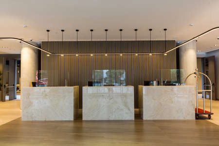 Interior of a hotel lobby with reception desks with transparent covid plexiglass lexan clear sneeze...