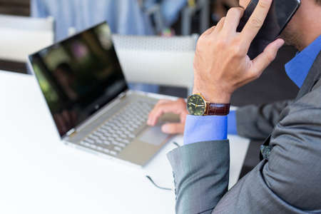Handsome businessman working on his laptop in the cafe bar, no faceの写真素材