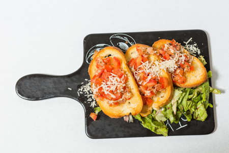 Tomato bruschetta served on black stone boardの写真素材