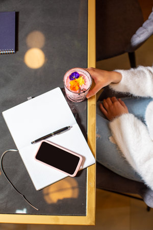 Top view of a woman alone drinking flower decorated smoothie at the restaurant