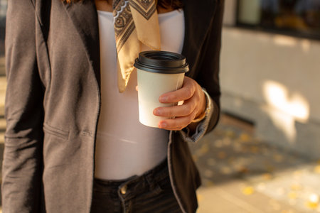 Beautiful woman with cup of coffee walking on street