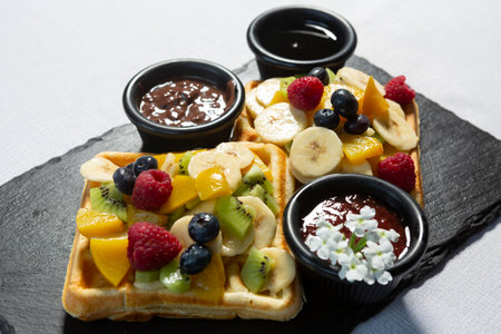 Waffle served on black stone  with fresh fruits and chocolateの写真素材