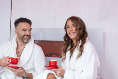 Handsome couple in bathrobe, drinking coffee in the hotel roomの写真素材