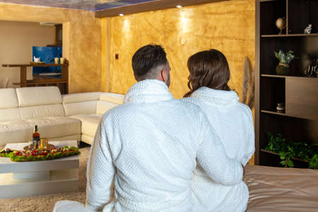 Romantic couple wearing bathrobe sitting on a hotel bed , backshot, no faceの写真素材